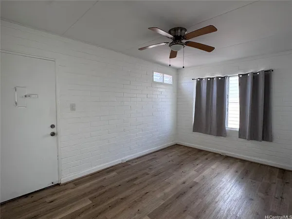 an empty room with wooden floor fan and windows