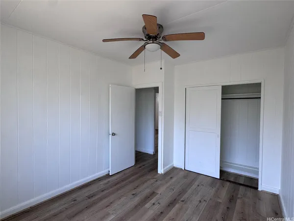 a view of an empty room with wooden floor and window