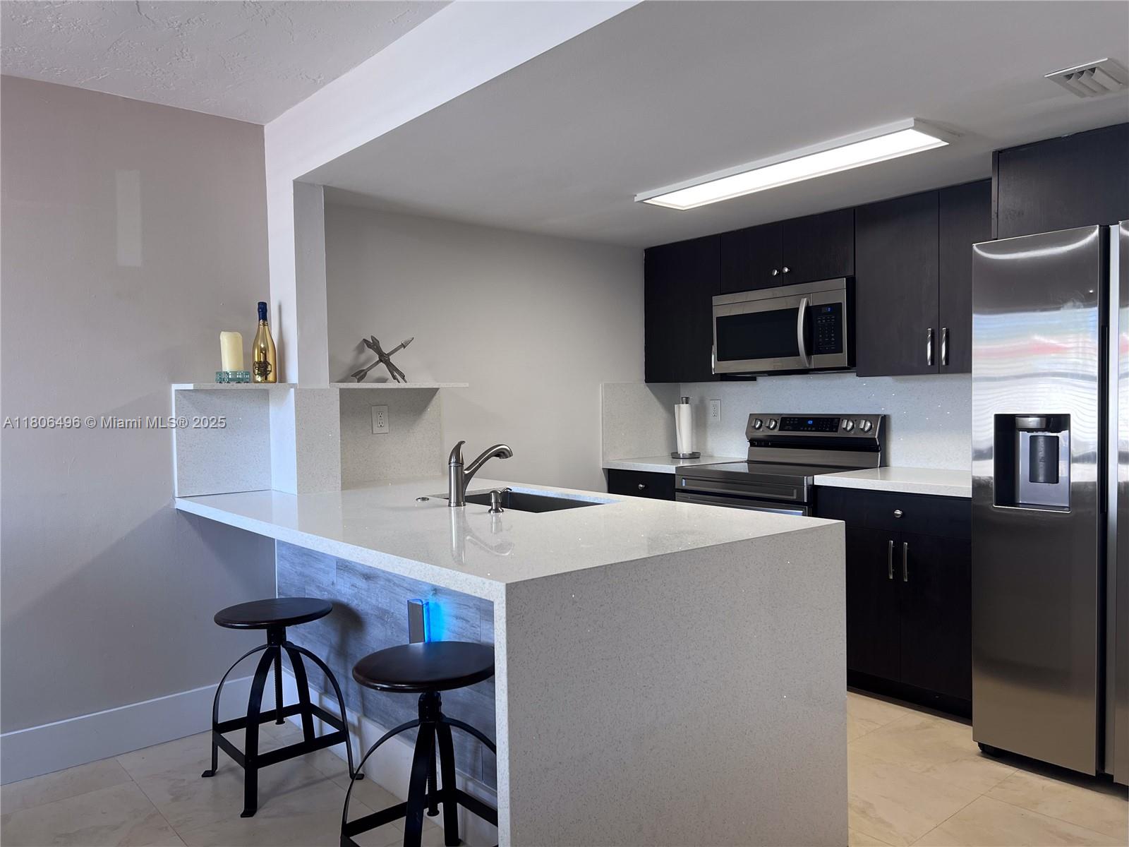4530 Southwest 68th Ct Circle, Unit 316 Miami, FL 33155 - Photo 9 of 26 a kitchen with stainless steel appliances a sink a stove a microwave a refrigerator and cabinets