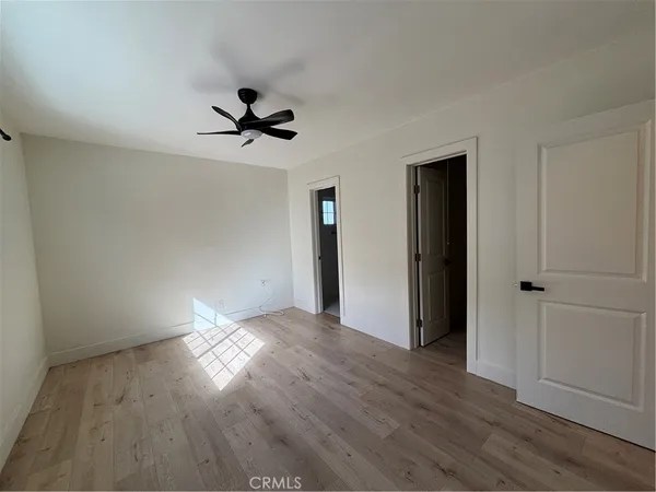 an empty room with wooden floor ceiling fan and windows