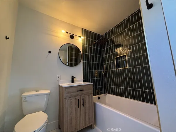 a bathroom with a toilet sink vanity tub and mirror