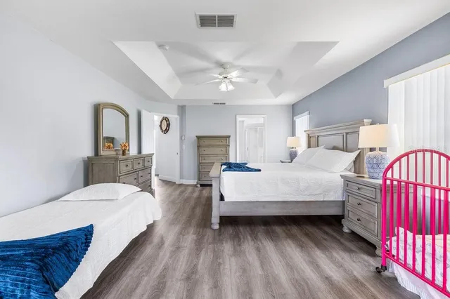 a spacious bedroom with a bed and dresser with mirror