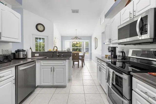a kitchen with stainless steel appliances granite countertop a stove a sink and a microwave