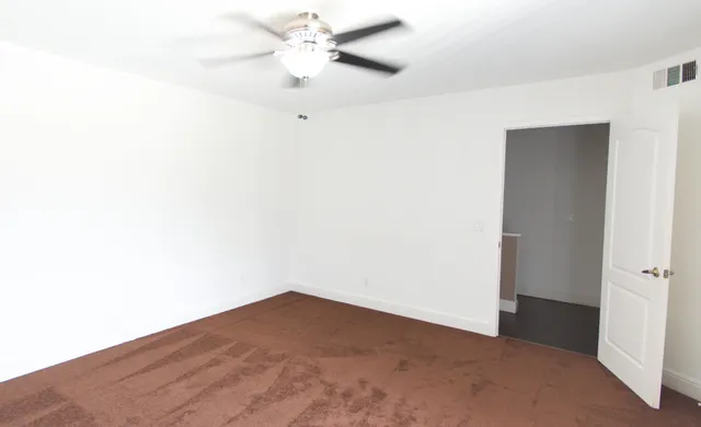 an empty room with a fan & a ceiling fan