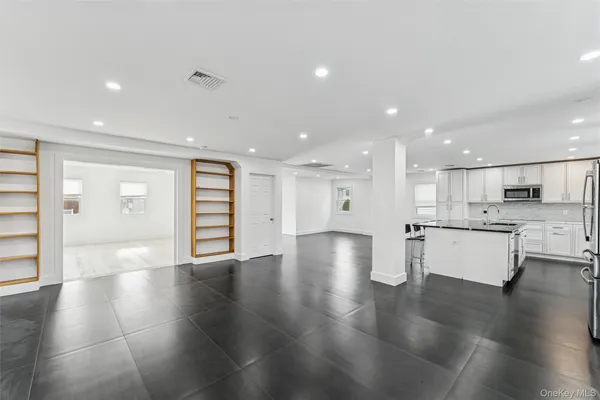 a kitchen with stainless steel appliances granite countertop a stove top oven a sink dishwasher a dining table and chairs with wooden floor
