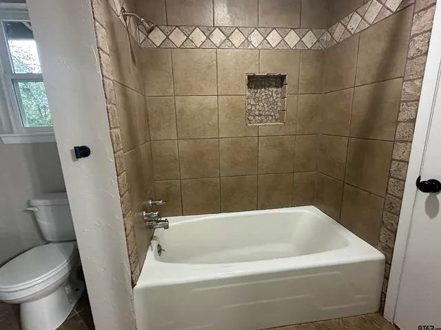a white bath tub sitting next to a toilet