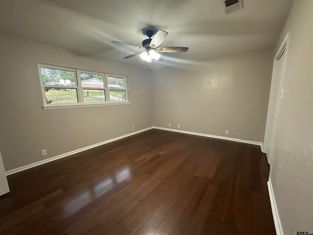 a view of wooden floor and a chandelier fan in a room