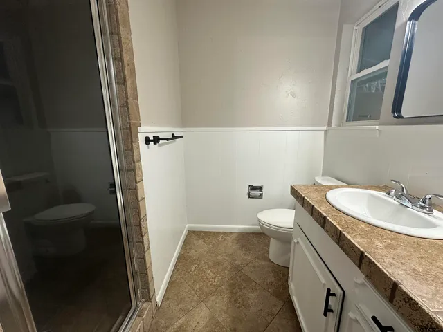 a bathroom with a granite countertop sink toilet and shower