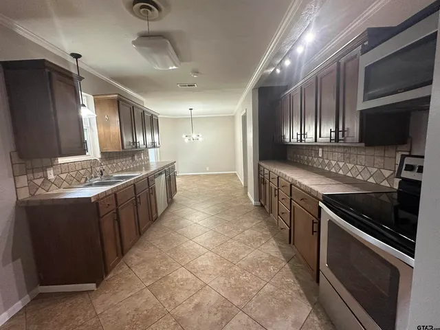 a large kitchen with stainless steel appliances kitchen island granite countertop a stove and a sink