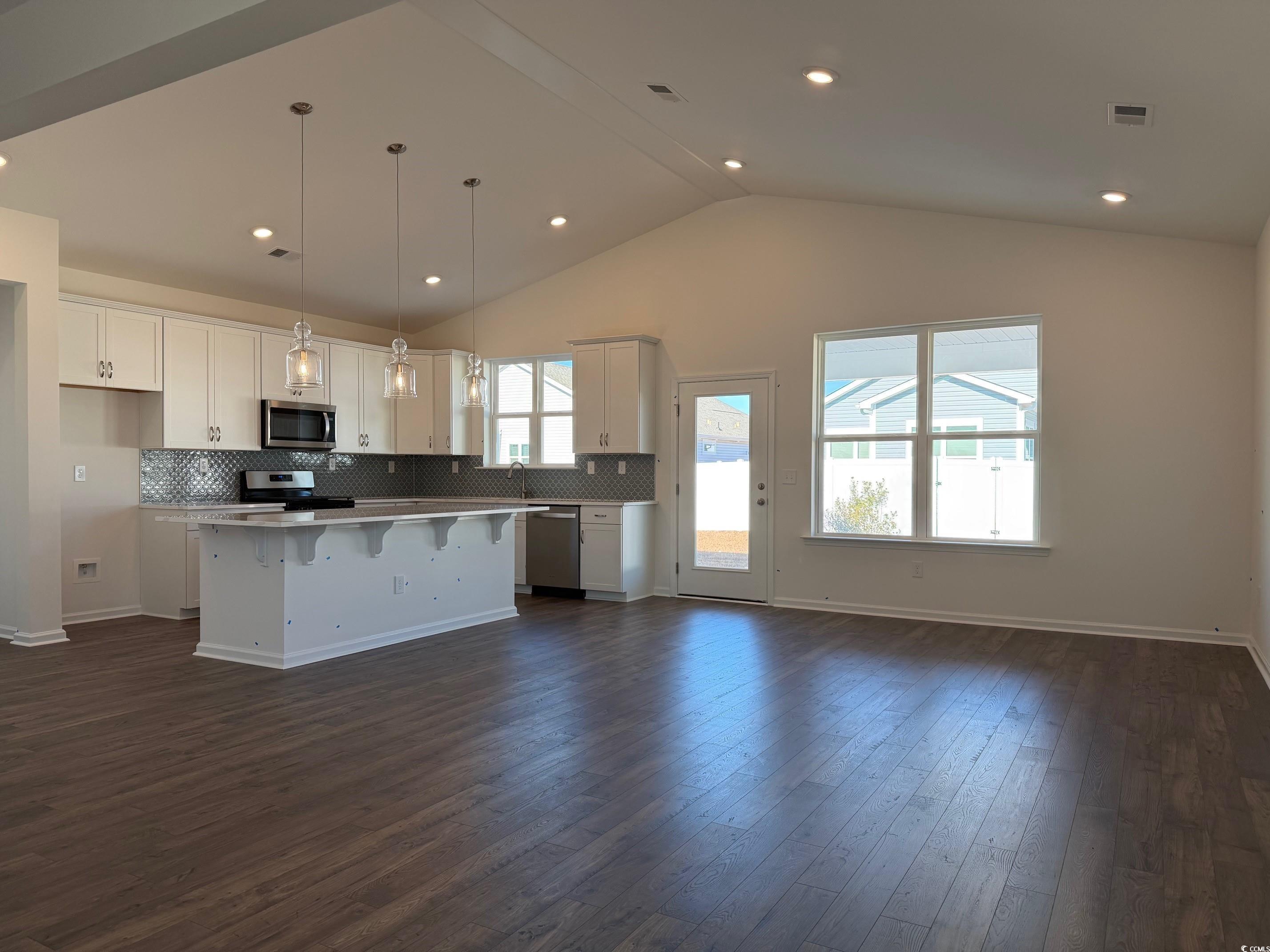 415 Kapalua Loop Little River, SC 29566 - Photo 2 of 19 Kitchen with tasteful backsplash, a breakfast bar area, appliances with stainless steel finishes, dark wood-style floors, and light stone counters