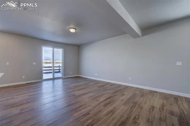 a view of an empty room with window and wooden floor