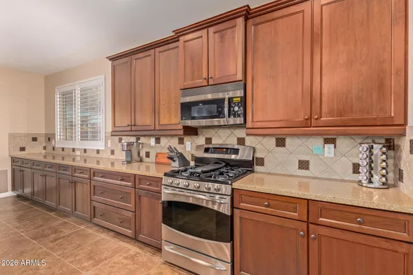 a kitchen with granite countertop a sink cabinets stainless steel appliances and a window