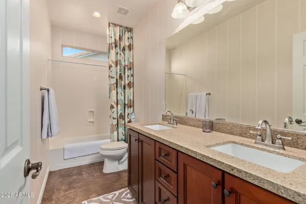 a bathroom with a granite countertop sink a toilet a mirror a vanity and shower