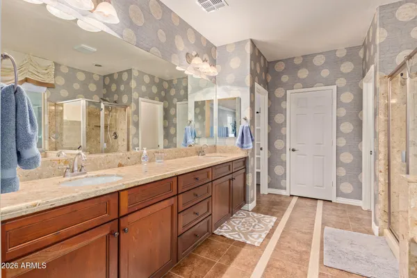 a spacious bathroom with a double vanity sink a mirror and a shower