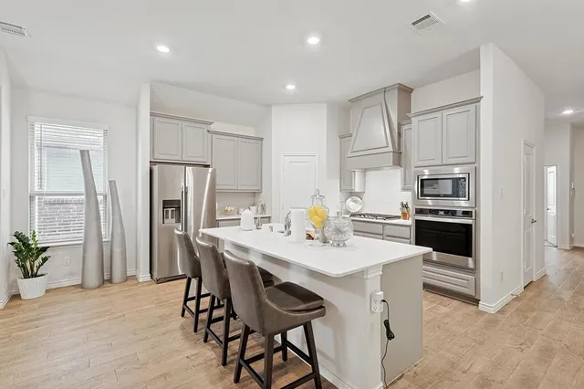 a kitchen with stainless steel appliances a table and chairs in it