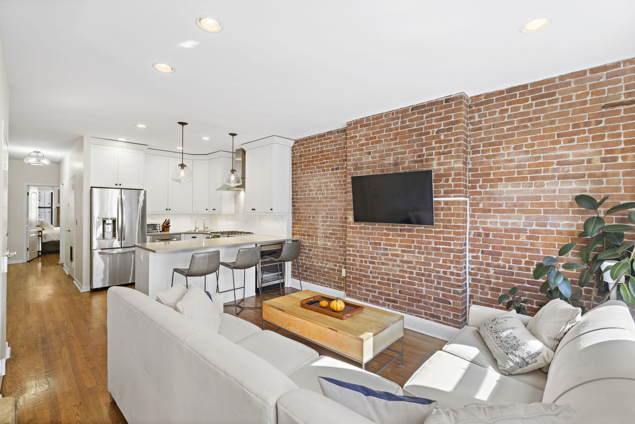 262 1st Street, Unit D Hoboken, NJ 07030 - Photo 3 of 19 a living room with couches a flat screen tv and kitchen view