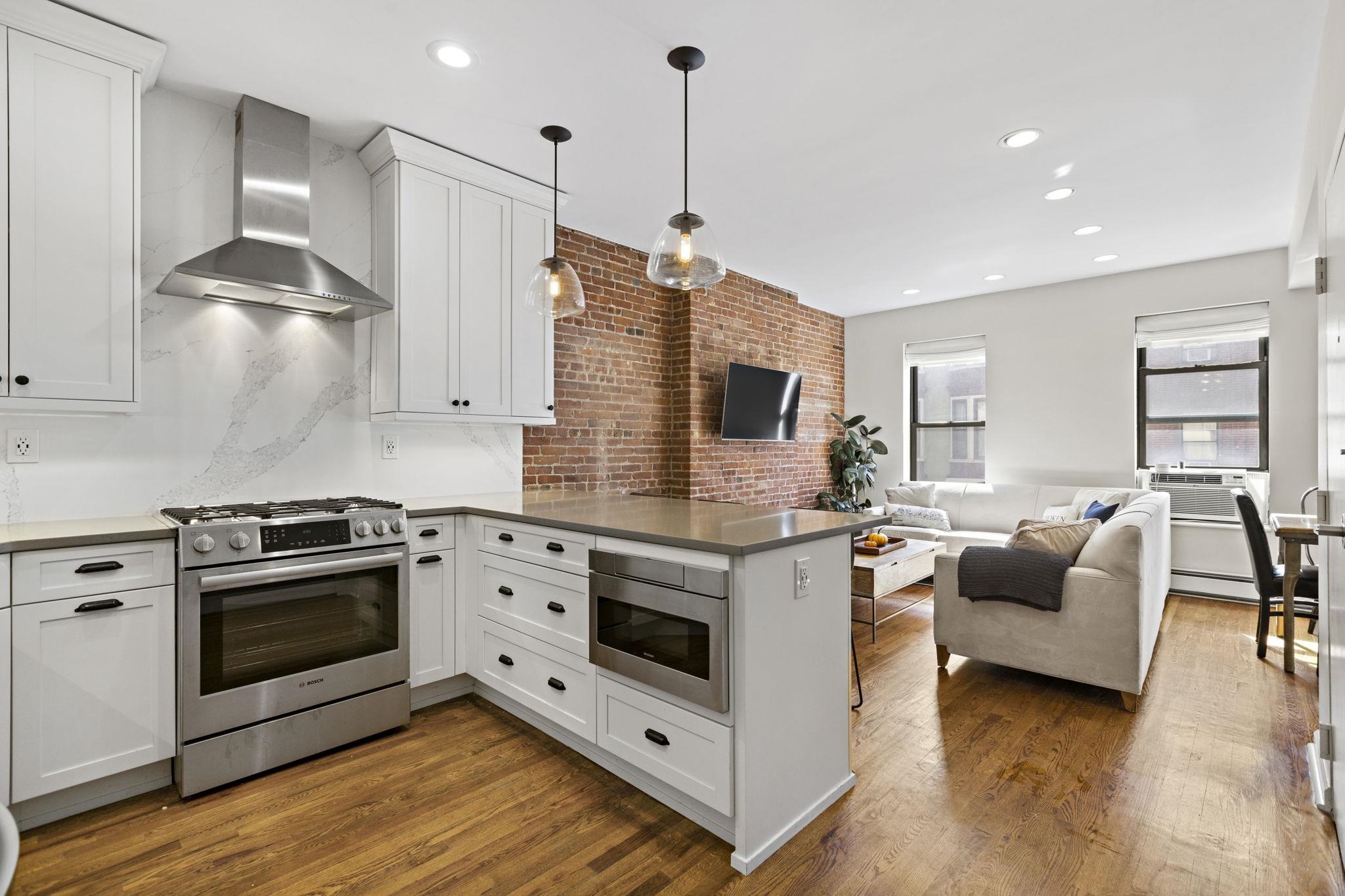 262 1st Street, Unit D Hoboken, NJ 07030 - Photo 5 of 19 a kitchen with stainless steel appliances white cabinets a stove a sink and a wooden floor