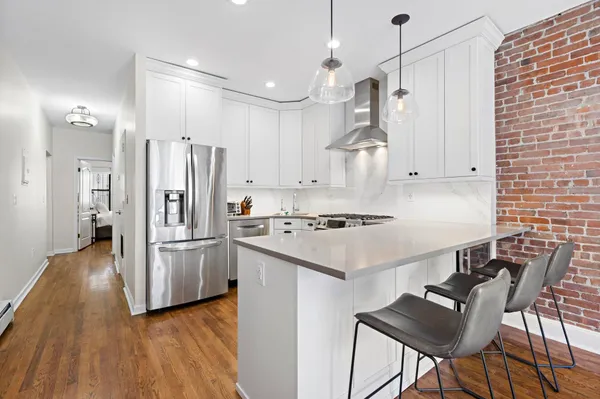 a kitchen with stainless steel appliances kitchen island a hardwood floor and chairs