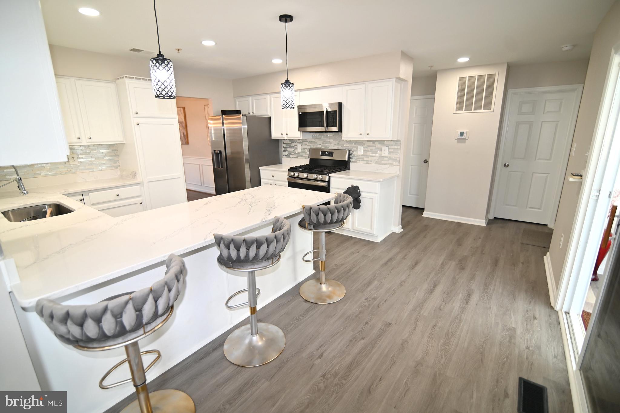 6009 Sellner Lane Clinton, MD 20735 - Photo 19 of 61 a kitchen with stainless steel appliances kitchen island granite countertop a refrigerator a stove a microwave oven a sink with island and chairs
