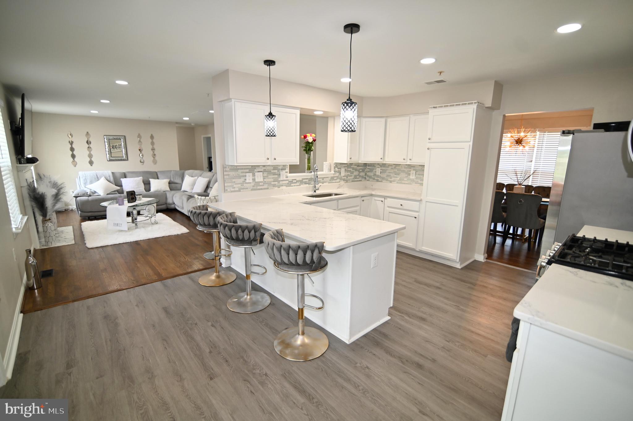 6009 Sellner Lane Clinton, MD 20735 - Photo 22 of 61 a living room with stainless steel appliances kitchen island granite countertop a stove a refrigerator a sink and a dining table with wooden floor