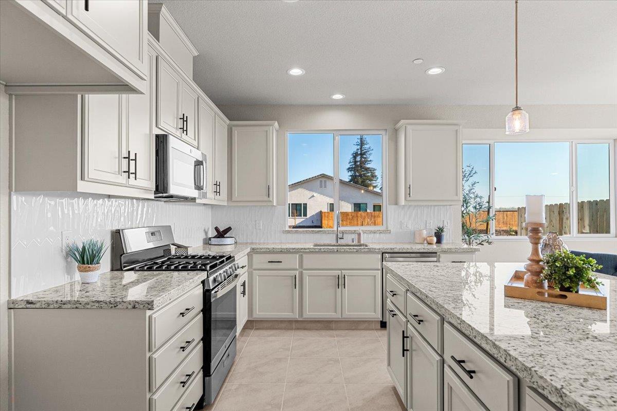 2970 East Tuolumne Road Turlock, CA 95382 - Photo 25 of 68 a kitchen with granite countertop a sink stove and cabinets
