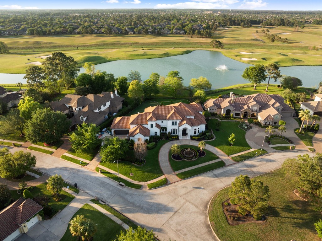 A striking aerial introduction to the estate, showcasing the circular drive, tile roof, manicured grounds, and commanding presence on a premier lake and golf course homesite. The setting immediately conveys the privacy, scale, and refined curb appeal expected in a luxury offering.