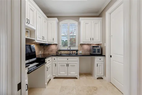 a large white kitchen with a large window and stainless steel appliances