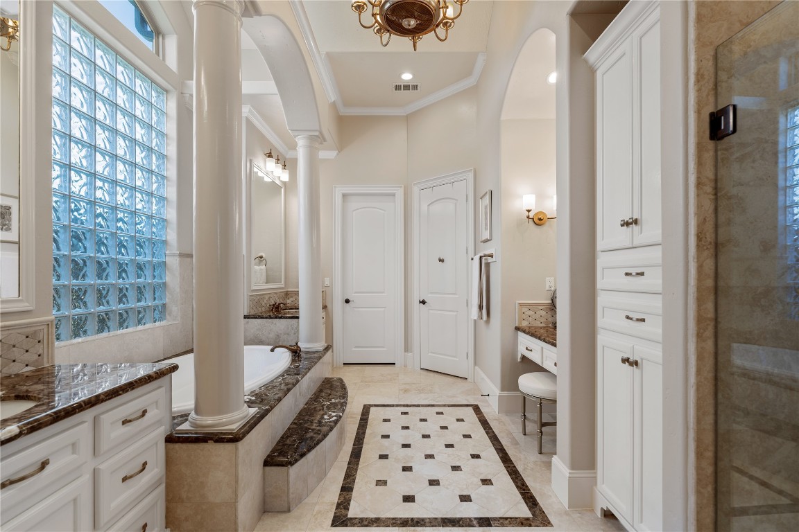 82 Manor Lake Estates Circle Spring, TX 77379 - Photo 28 of 50 The primary bath offers a spacious, spa like layout with marble topped vanities, a jetted soaking tub, and architectural columns that add a sense of grandeur. The glass block wall brings in soft natural light while maintaining privacy, creating a serene daily retreat.