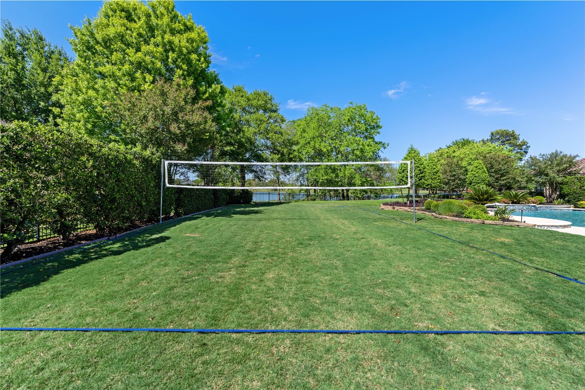82 Manor Lake Estates Circle Spring, TX 77379 - Photo 42 of 50 The full size grass sport court adds a rare recreational feature, offering space for volleyball, lawn games, and active outdoor living. Surrounded by mature landscaping and privacy hedges, it brings both versatility and fun to the backyard experience.