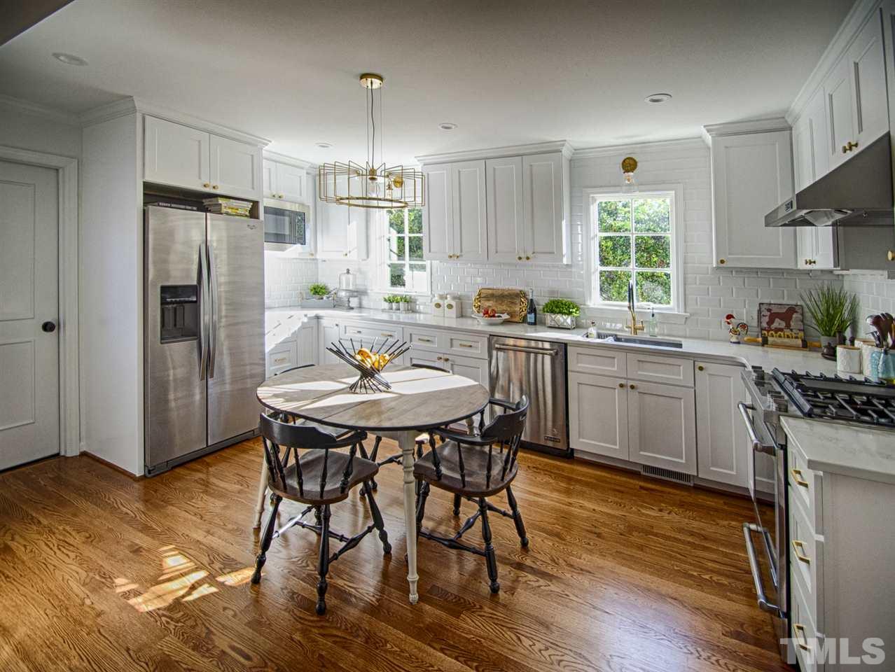 2324 Ridge Road Raleigh, NC 27612 - Photo 6 of 25 a kitchen with stainless steel appliances a dining table chairs refrigerator sink and cabinets