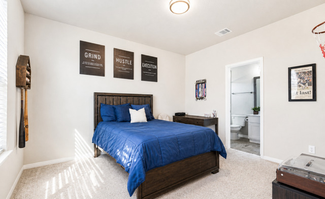 1928 Lakeside Ranch Road Georgetown, TX 78633 - Photo 28 of 37 A well-appointed bedroom featuring light-colored carpeting, a dark wooden bed frame, and an adjoining private bathroom.