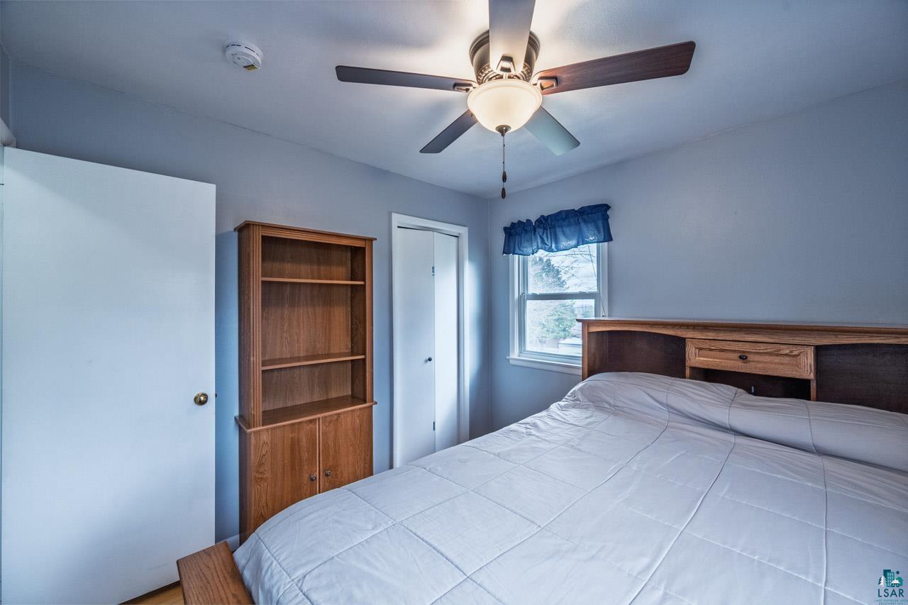 319 Michigan Avenue West Gilbert, MN 55741 - Photo 13 of 48 Bedroom featuring a ceiling fan with light fixture, light blue wall paint, a window with valance, and wood-finish flooring