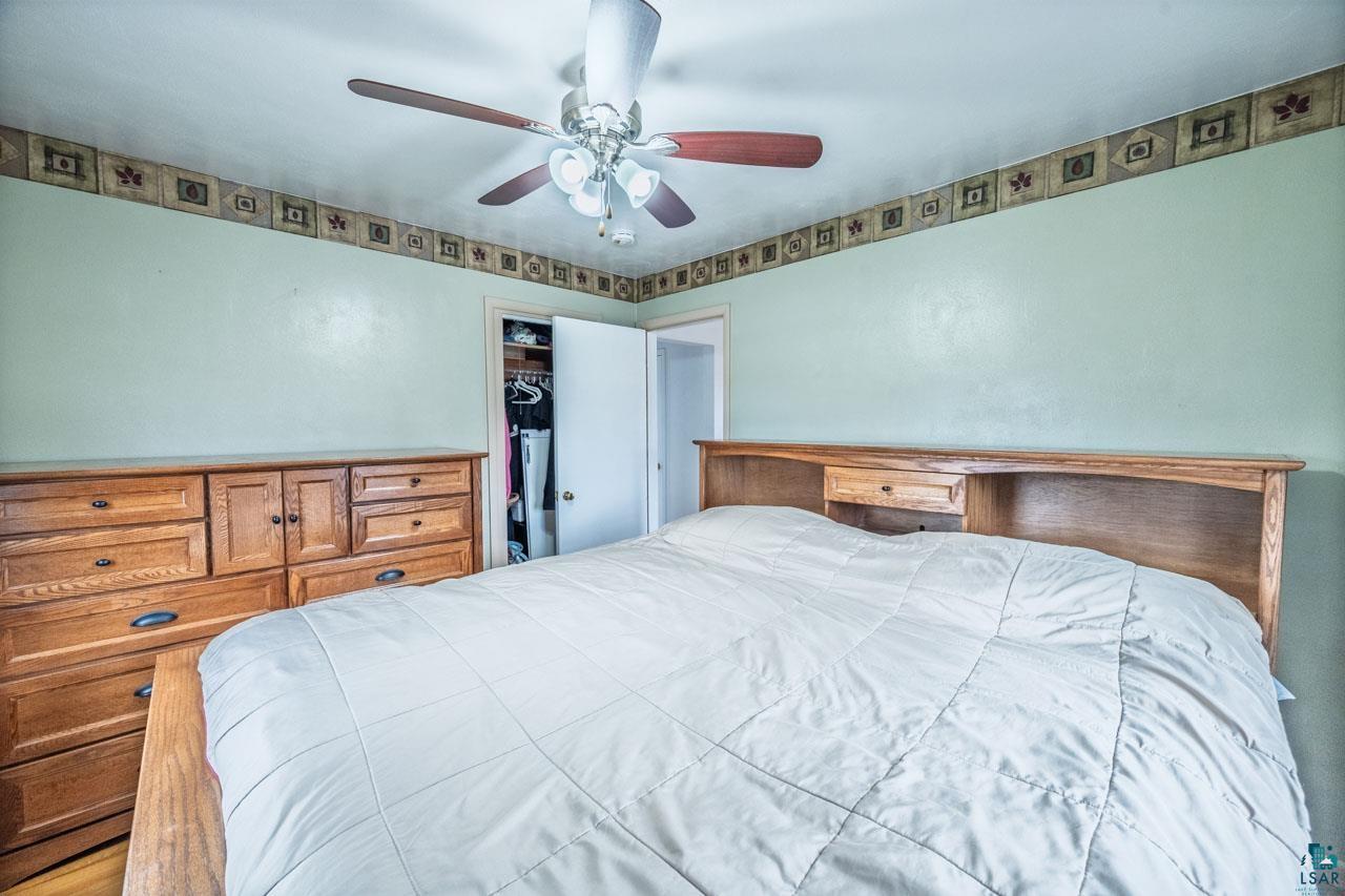319 Michigan Avenue West Gilbert, MN 55741 - Photo 17 of 48 Bedroom featuring light green walls with decorative border, a ceiling fan with light kit, and a closet with a white door