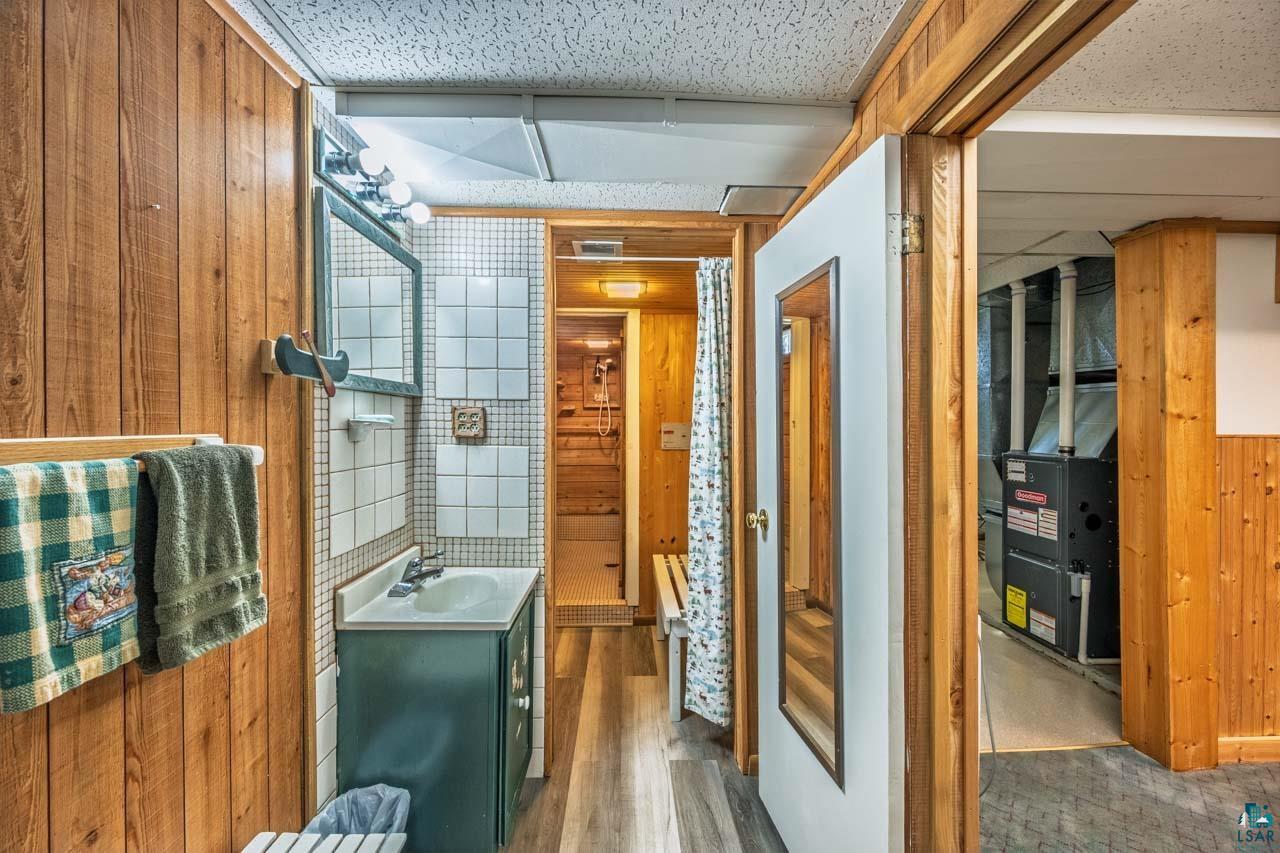 319 Michigan Avenue West Gilbert, MN 55741 - Photo 20 of 48 Bathroom featuring wood-finish paneling, a vanity with a rectangular basin, and a tiled backsplash
