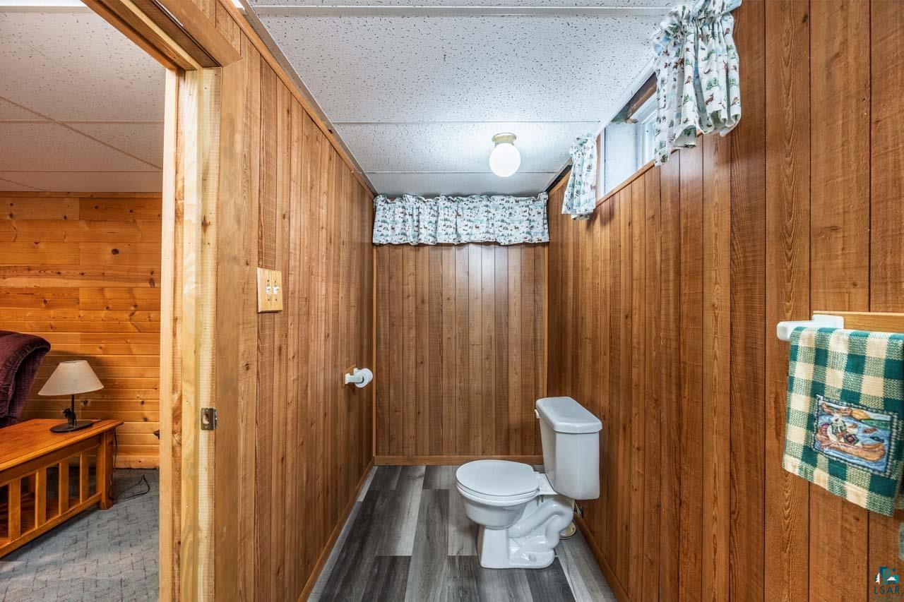 319 Michigan Avenue West Gilbert, MN 55741 - Photo 22 of 48 Powder room featuring wood-paneled walls, a white toilet, and wood-finish flooring