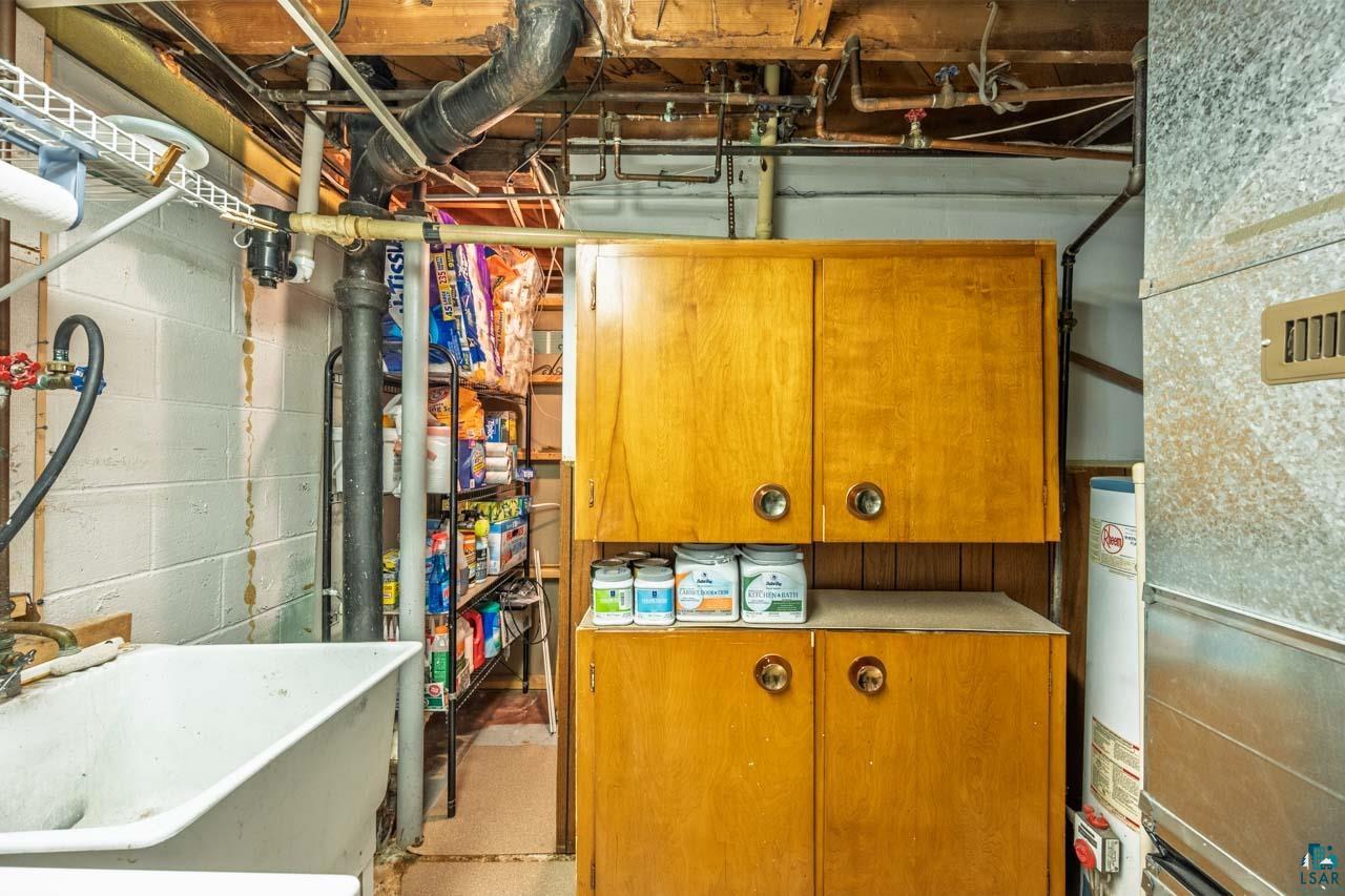 319 Michigan Avenue West Gilbert, MN 55741 - Photo 26 of 48 Utility area featuring a laundry sink, wood-finish cabinetry, and exposed ceiling joists