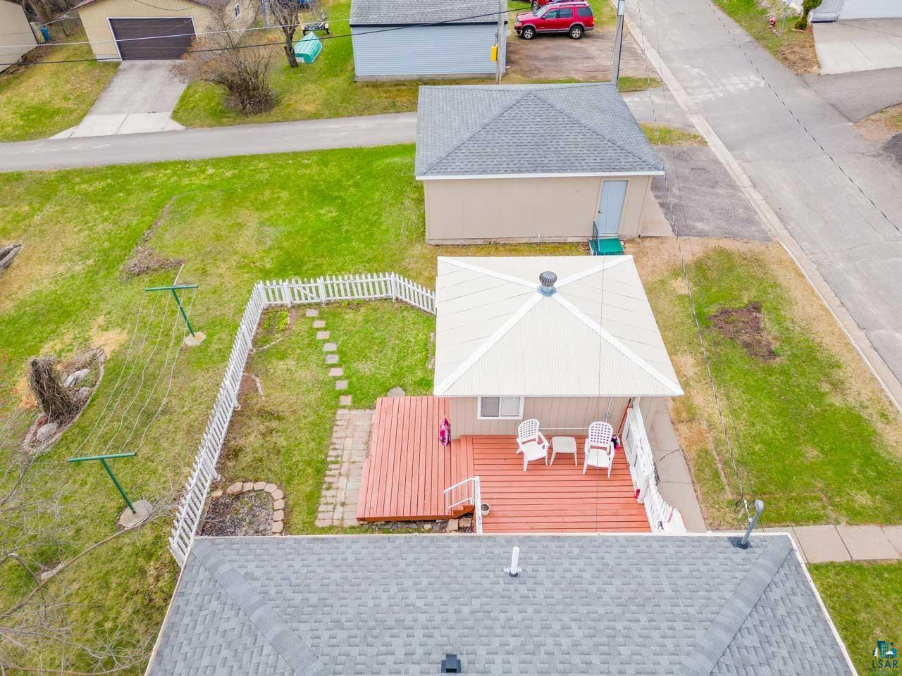 319 Michigan Avenue West Gilbert, MN 55741 - Photo 45 of 48 Fenced backyard featuring a wood deck, stone pathway, and a detached outbuilding with a gray shingle roof