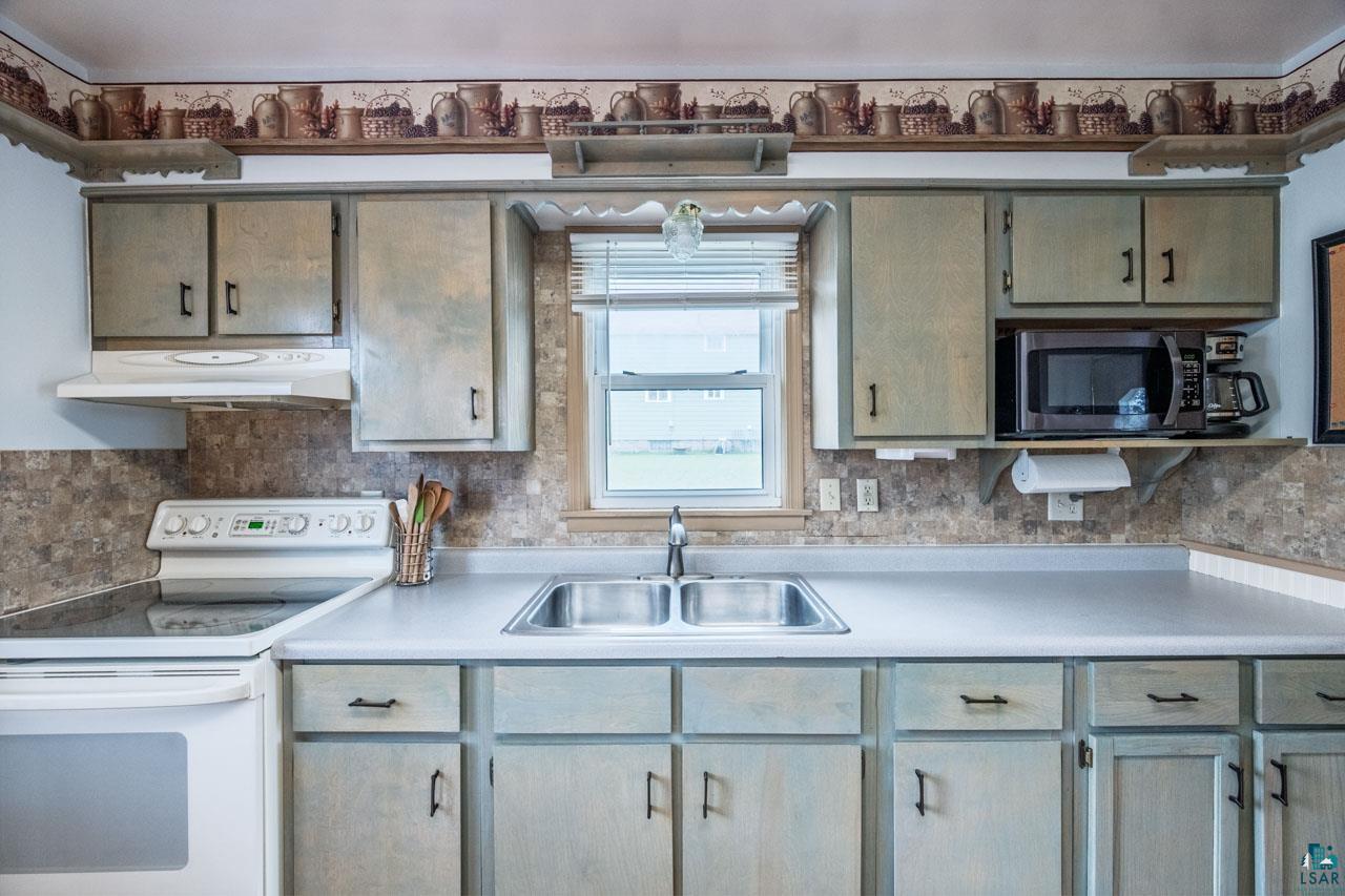 319 Michigan Avenue West Gilbert, MN 55741 - Photo 8 of 48 Kitchen featuring ample cabinetry, a double basin sink with a window overhead, light-toned countertops, and a full range with an overhead exhaust fan