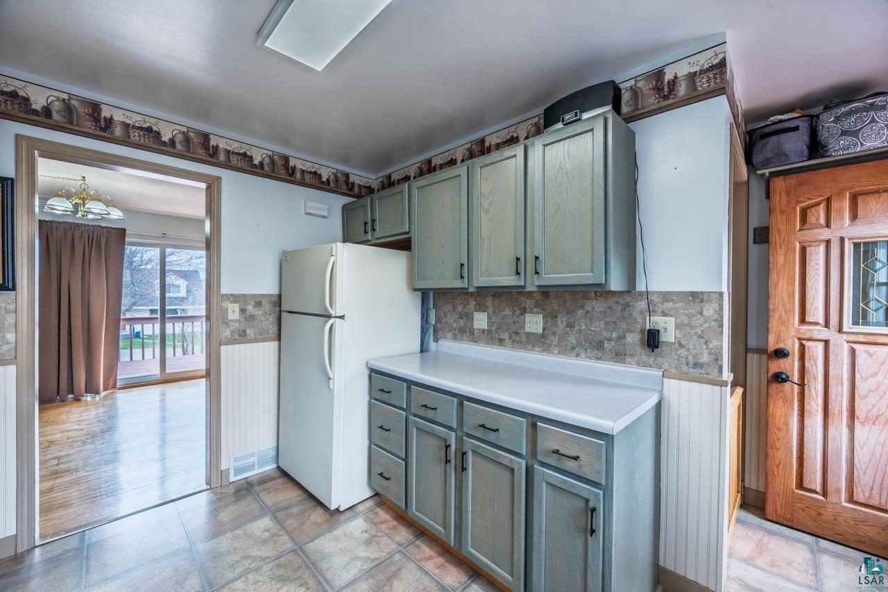 319 Michigan Avenue West Gilbert, MN 55741 - Photo 10 of 48 Kitchen area featuring light blue cabinetry with dark hardware, white countertops, and a tile backsplash