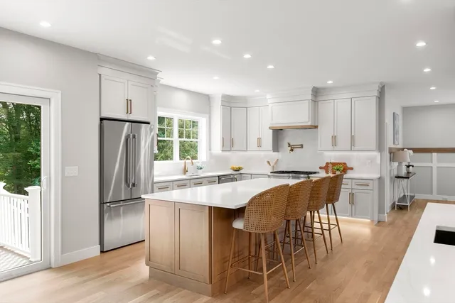 a kitchen with stainless steel appliances granite countertop a refrigerator a sink a stove a dining table and chairs