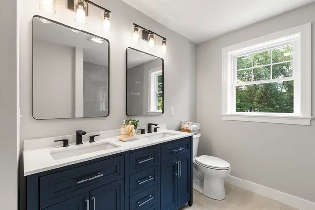 a bathroom with a double vanity sink toilet and a mirror