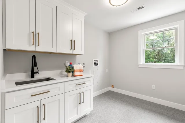 a kitchen with white cabinets and window