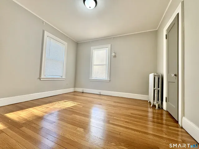 a view of an empty room with window and wooden floor