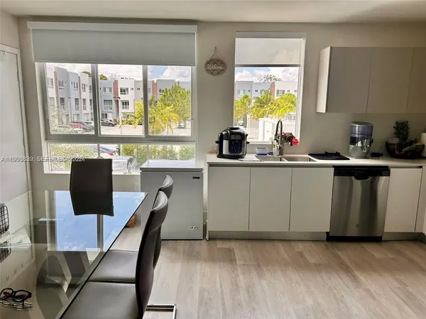 a kitchen with stainless steel appliances a table chairs and a window