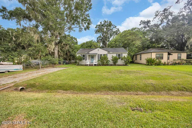 a view of a house with a big yard and large trees