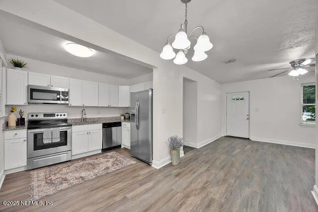 a kitchen with stainless steel appliances granite countertop a refrigerator a sink and white cabinets