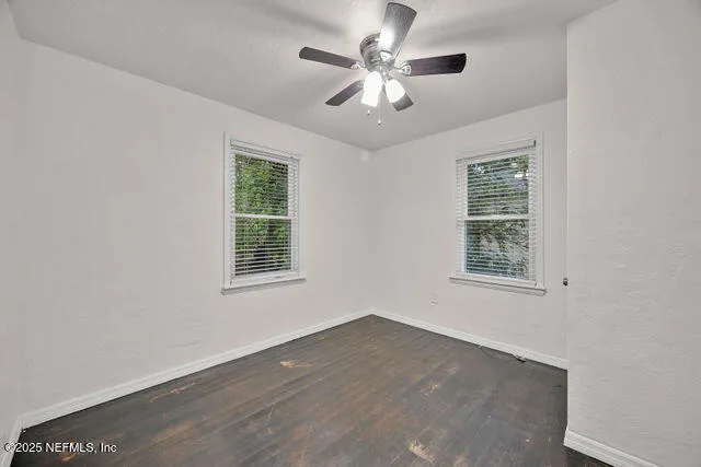 an empty room with wooden floor and ceiling fan