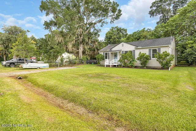a view of a house with a big yard and palm trees