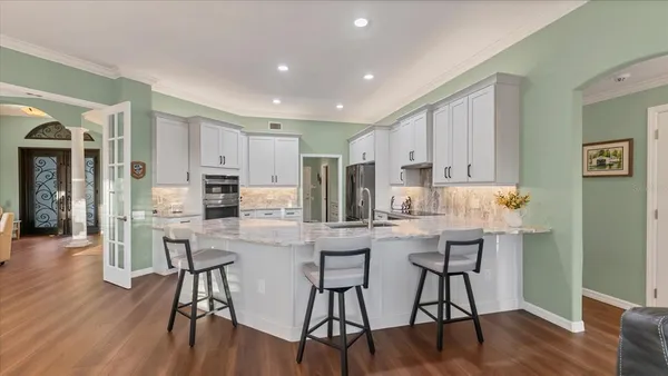 a kitchen with stainless steel appliances a dining table chairs and wooden floor