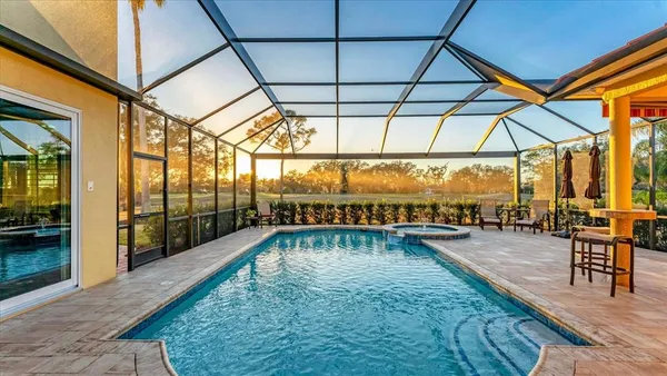 a swimming pool with lawn chairs under an umbrella